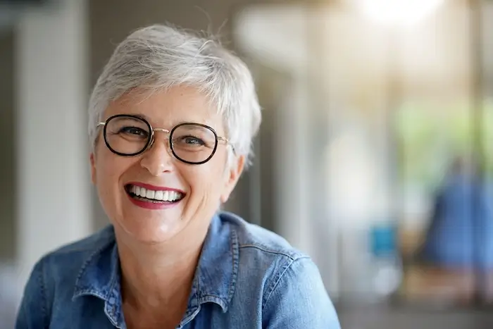 Silver haired woman with dark round glasses smiling